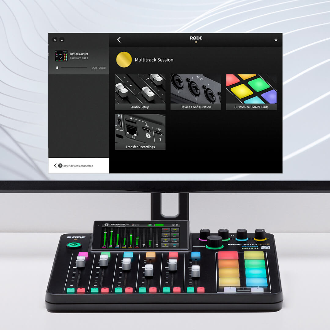 RØDECaster Pro II in front of a monitor running the RØDECaster App, showing the Audio Setup, Device Configuration, Customise SMART Pads and Transfer Recordings tiles.